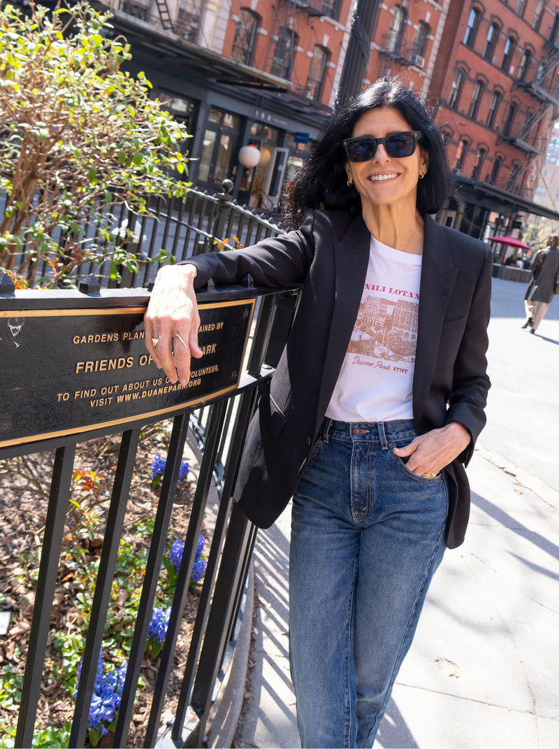 Woman in sunglasses leaning on a fence in an urban setting.